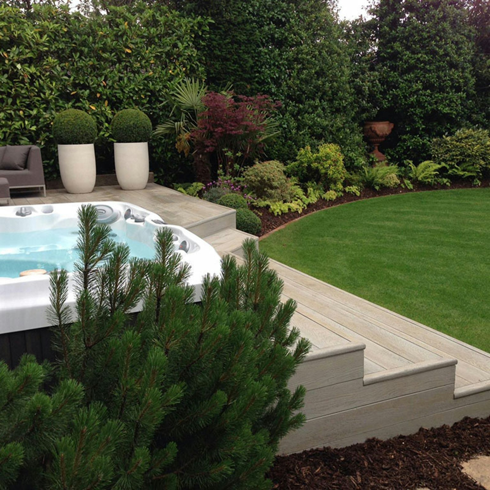 Hot tub on a deck surrounded by lush garden