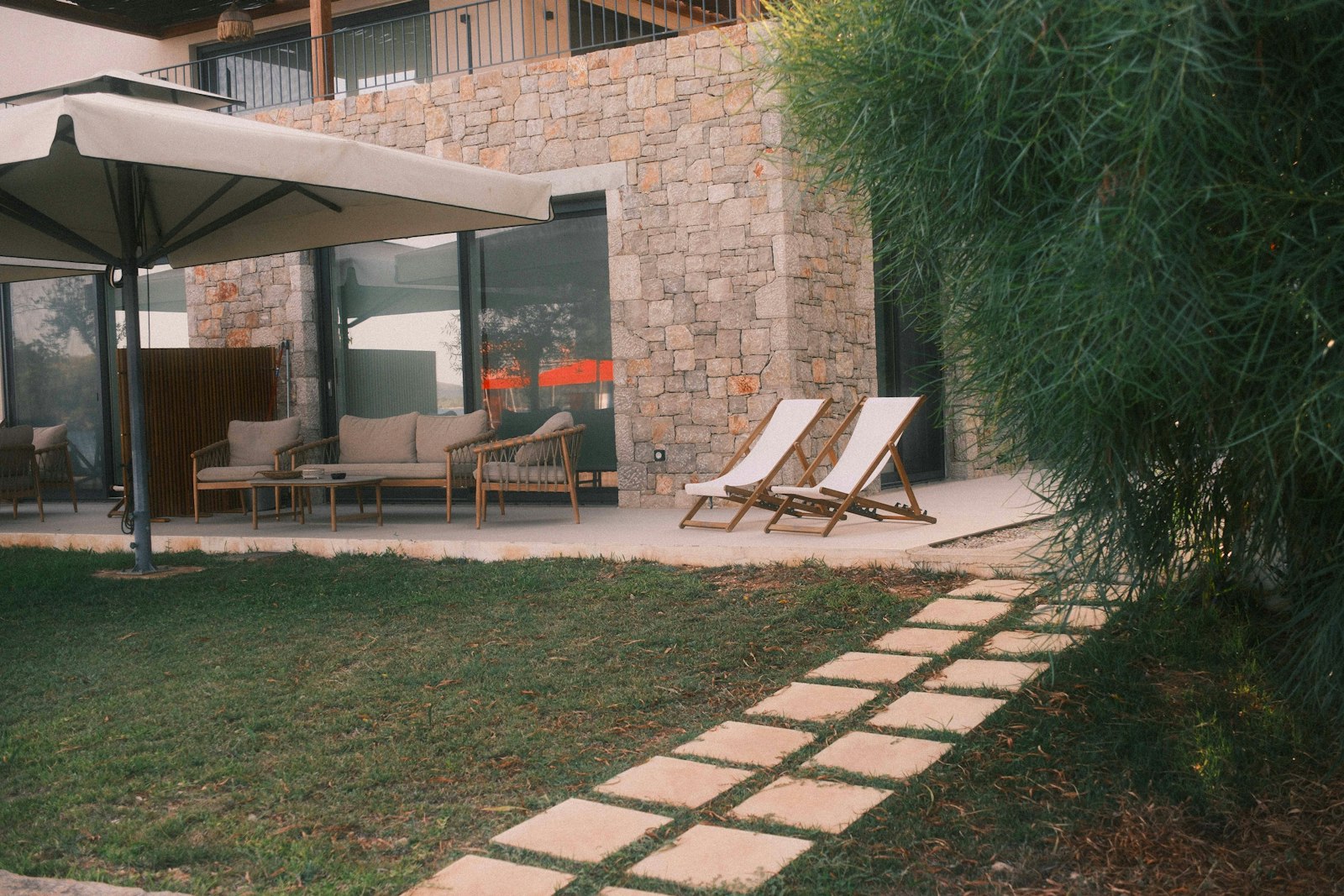 Lounge chairs on a stone patio beside a lawn